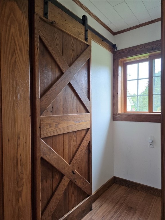 interior space featuring a barn door, ornamental molding, and hardwood / wood-style floors