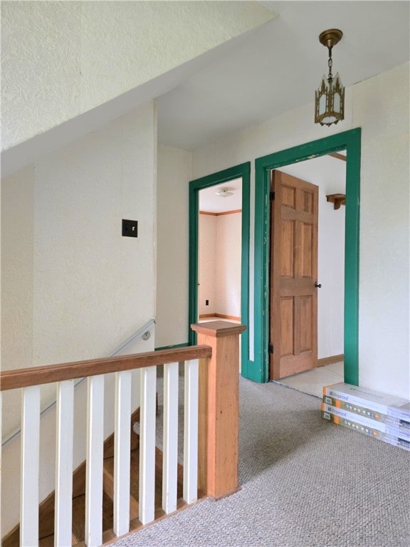 corridor with an inviting chandelier and carpet