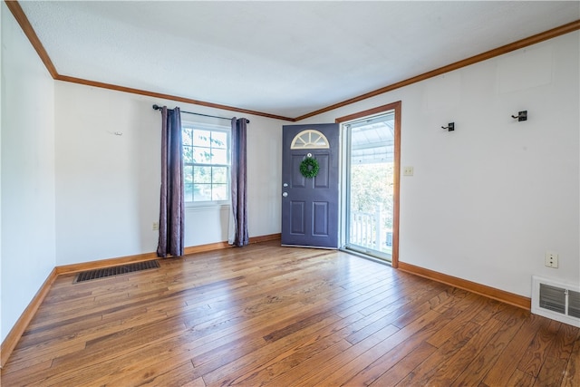 foyer featuring a wealth of natural light, ornamental molding, and hardwood / wood-style flooring