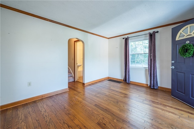 interior space featuring wood-type flooring, a textured ceiling, and ornamental molding