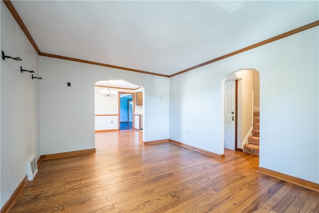 empty room featuring hardwood / wood-style flooring, crown molding, and a notable chandelier