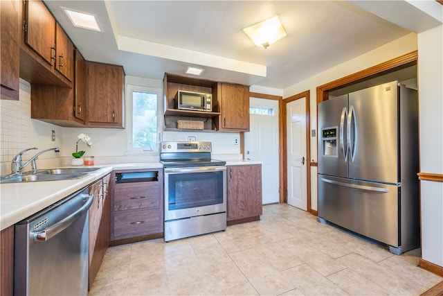 kitchen with backsplash, sink, light tile patterned flooring, and stainless steel appliances