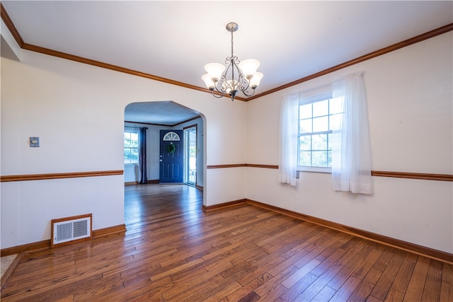 empty room with a notable chandelier, plenty of natural light, dark hardwood / wood-style floors, and crown molding