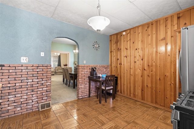 carpeted dining space with wooden walls