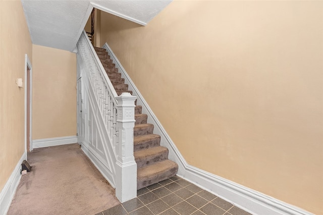 stairs featuring a textured ceiling and carpet floors