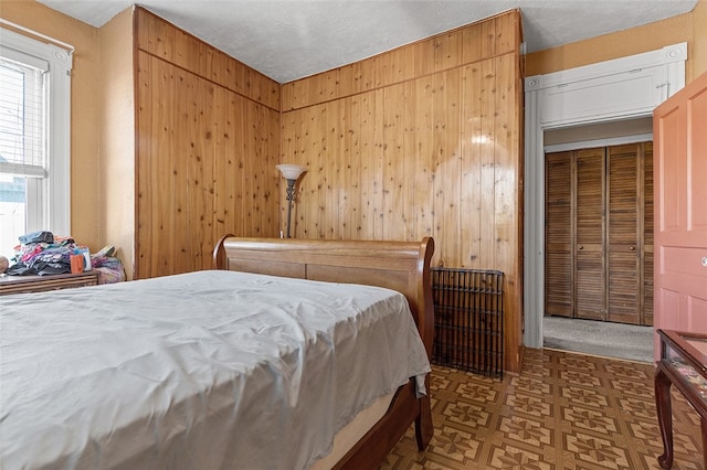 bedroom featuring a textured ceiling and wood walls