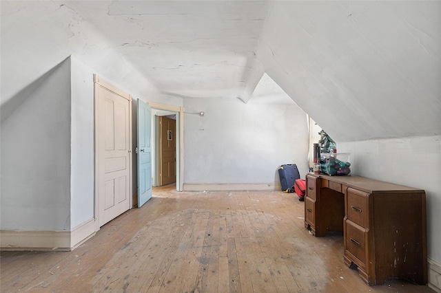 additional living space with light hardwood / wood-style floors and vaulted ceiling