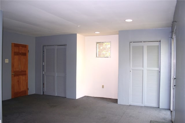 unfurnished bedroom featuring carpet flooring and multiple closets