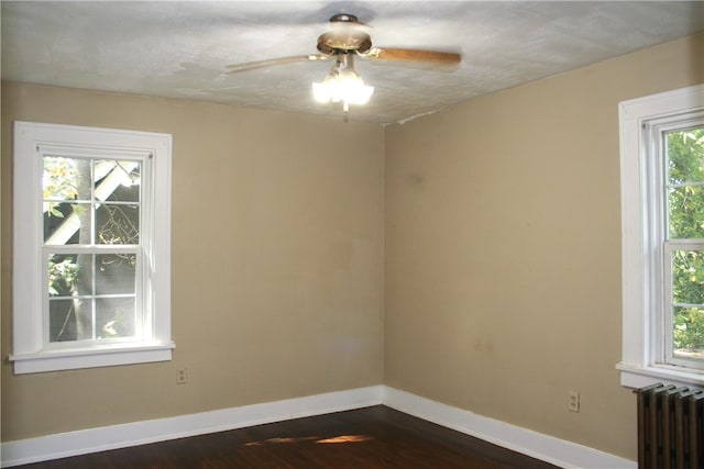 spare room featuring radiator, dark hardwood / wood-style flooring, and plenty of natural light