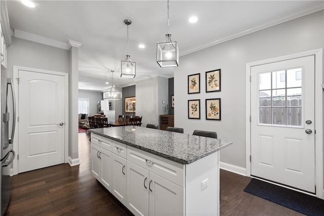 kitchen featuring white cabinets, a kitchen island, hanging light fixtures, and dark wood-type flooring