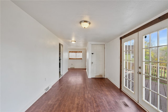 corridor with french doors, dark hardwood / wood-style floors, and a textured ceiling