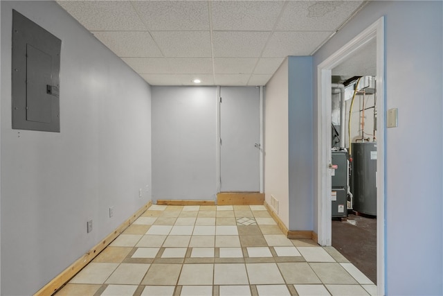 spare room featuring electric panel, water heater, light tile patterned floors, and a drop ceiling