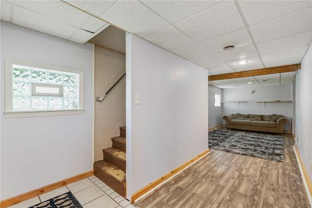 basement with a drop ceiling and light hardwood / wood-style flooring