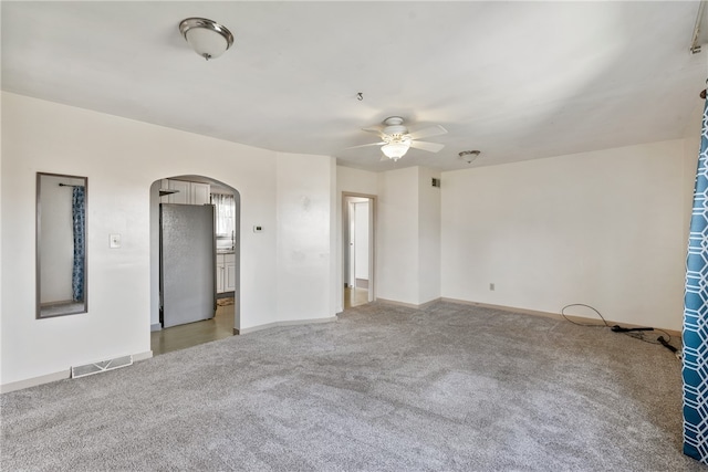 unfurnished room featuring visible vents, baseboards, light carpet, arched walkways, and a ceiling fan