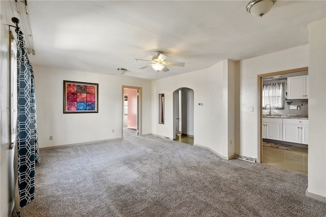 carpeted empty room featuring ceiling fan and sink