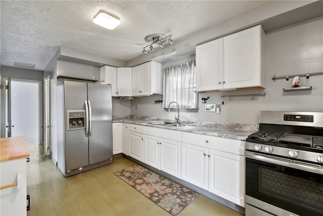 kitchen featuring light hardwood / wood-style flooring, appliances with stainless steel finishes, sink, and white cabinets