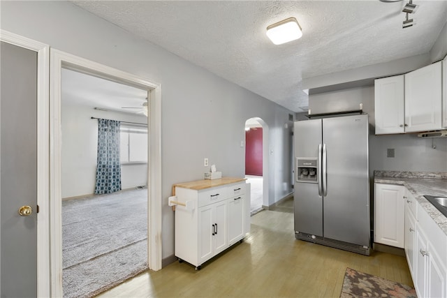 kitchen with white cabinets, light hardwood / wood-style flooring, a textured ceiling, and stainless steel fridge