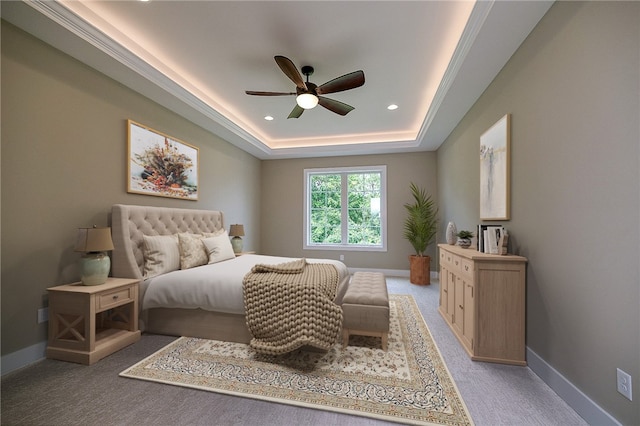 carpeted bedroom with a tray ceiling and ceiling fan