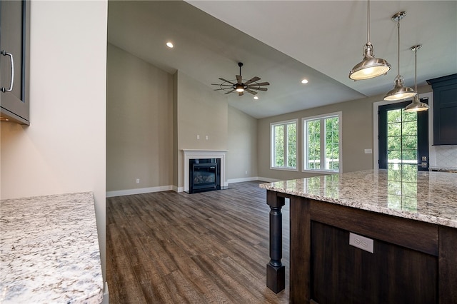 kitchen featuring light stone counters, ceiling fan, lofted ceiling, decorative light fixtures, and dark hardwood / wood-style floors