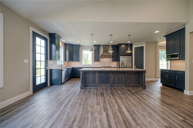 kitchen with stainless steel appliances, a wealth of natural light, a kitchen island, and custom exhaust hood