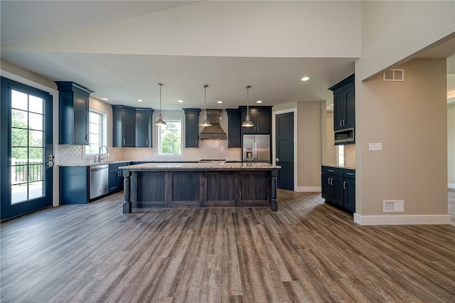 kitchen with a center island, custom exhaust hood, backsplash, appliances with stainless steel finishes, and dark hardwood / wood-style flooring