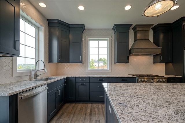 kitchen featuring light stone counters, dark wood-type flooring, sink, custom range hood, and appliances with stainless steel finishes