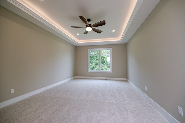 carpeted spare room with ornamental molding, a tray ceiling, and ceiling fan