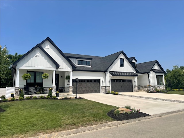 modern farmhouse style home with a front yard, a garage, and covered porch