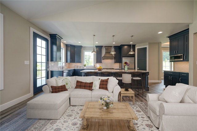 living room featuring lofted ceiling, hardwood / wood-style floors, a healthy amount of sunlight, and sink