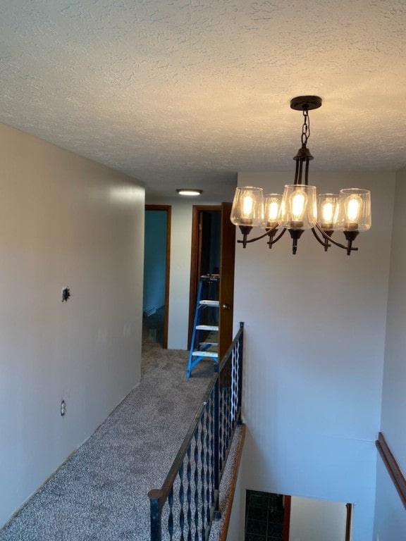 stairs with carpet floors, a textured ceiling, and a notable chandelier