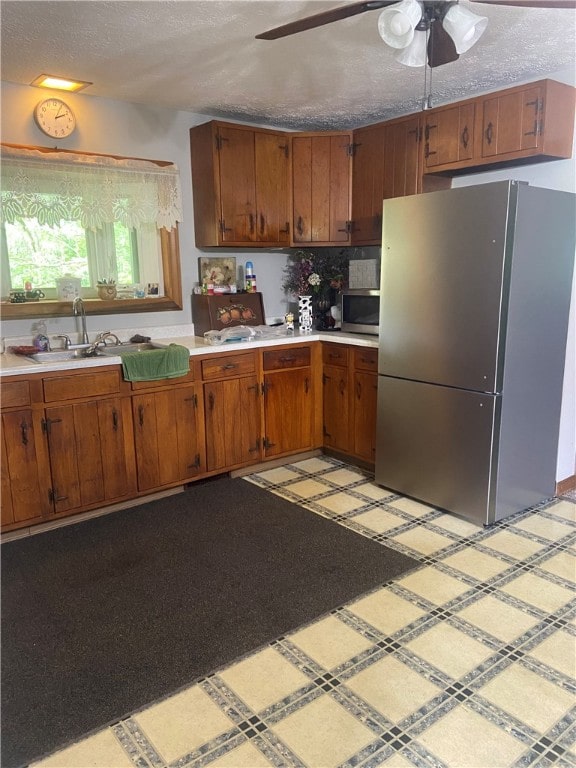 kitchen with decorative backsplash, stainless steel appliances, a textured ceiling, ceiling fan, and sink