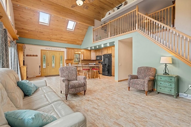 living room featuring ceiling fan, wood ceiling, high vaulted ceiling, and a skylight