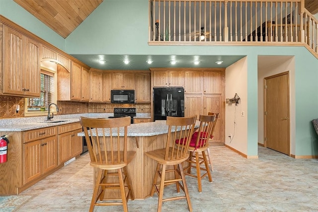 kitchen featuring high vaulted ceiling, black appliances, sink, a kitchen island, and a kitchen bar