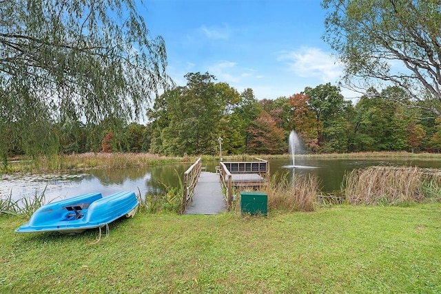 view of dock with a lawn and a water view