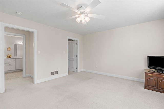 bedroom featuring light colored carpet, ensuite bath, and ceiling fan