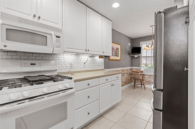 kitchen with white cabinets, light tile patterned flooring, white appliances, decorative light fixtures, and decorative backsplash