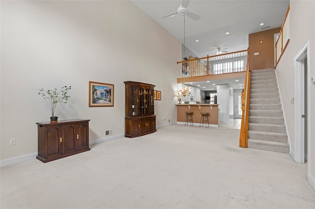 carpeted living room featuring high vaulted ceiling, ceiling fan, and bar area