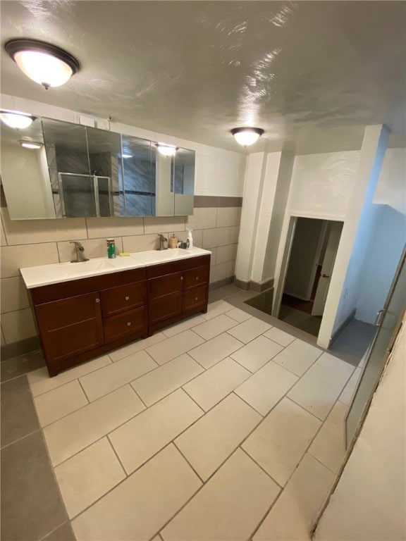 bathroom featuring vanity, an enclosed shower, tile walls, and tile patterned floors