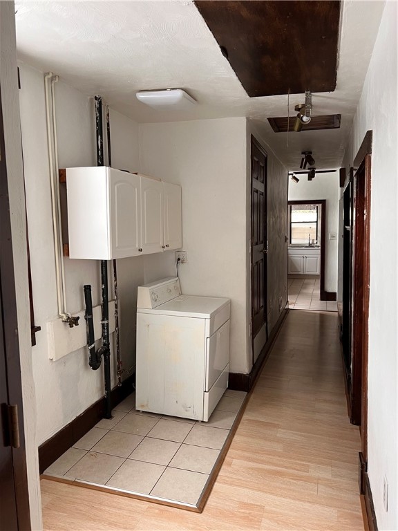 laundry room with cabinets, light wood-type flooring, and washer / clothes dryer