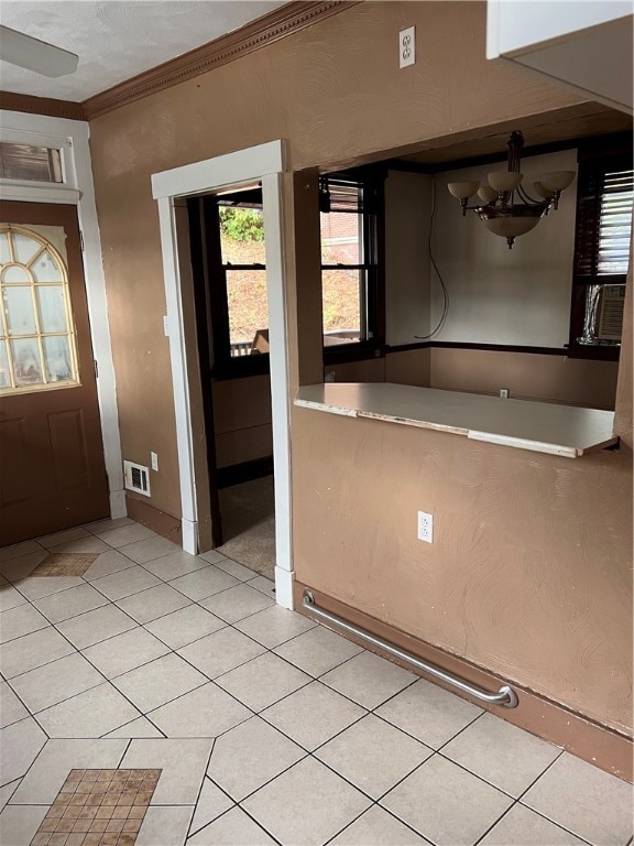 kitchen with light tile patterned floors, ceiling fan with notable chandelier, and crown molding