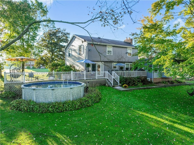 rear view of house featuring a pool side deck and a lawn