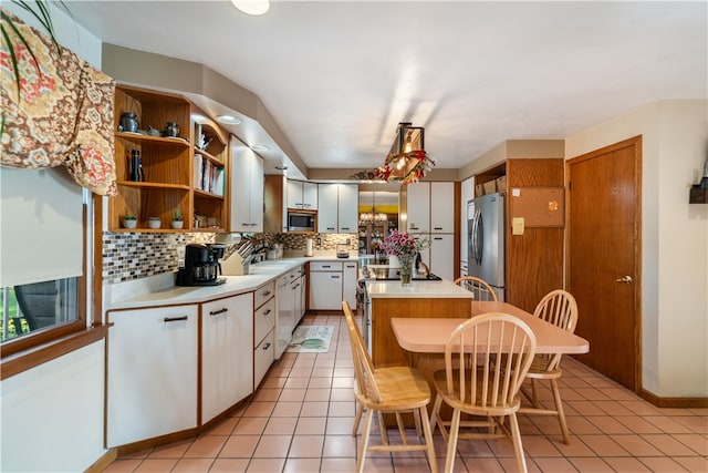 kitchen featuring tasteful backsplash, a breakfast bar, stainless steel appliances, light tile patterned floors, and white cabinetry