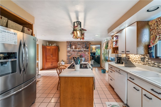 kitchen featuring a brick fireplace, white dishwasher, white cabinets, stainless steel fridge with ice dispenser, and a center island