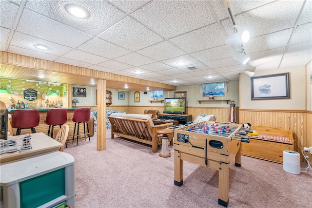 recreation room featuring carpet floors, bar area, wood walls, and a paneled ceiling