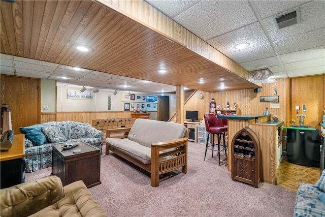 living room featuring a drop ceiling, carpet, and indoor bar