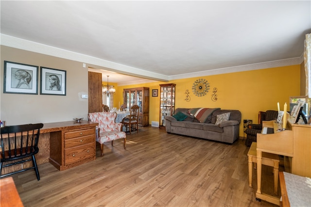 living room with hardwood / wood-style flooring, a notable chandelier, and crown molding