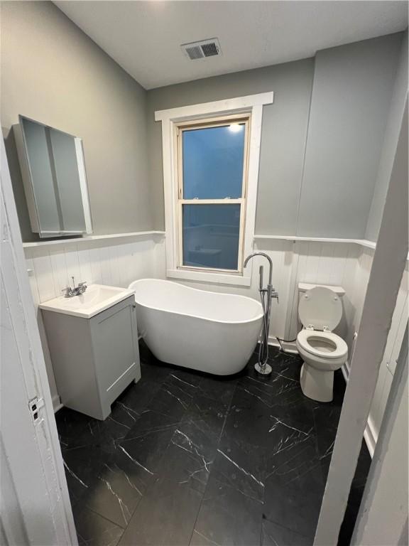 bathroom featuring a bath, vanity, and toilet