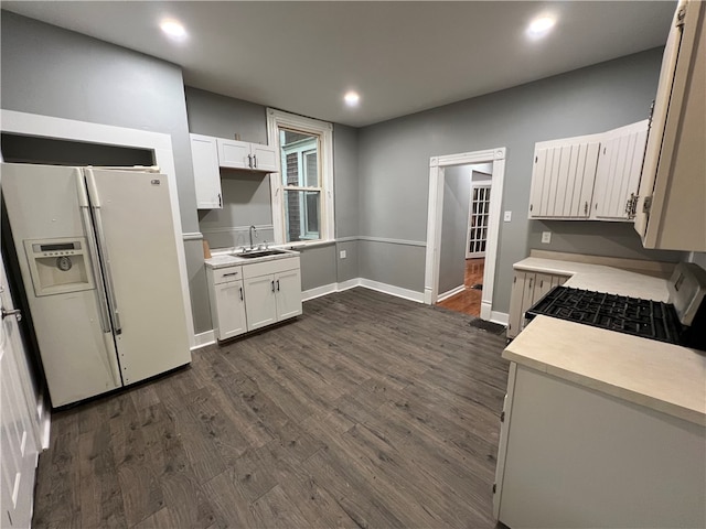 kitchen with white refrigerator with ice dispenser, sink, dark hardwood / wood-style floors, and white cabinets