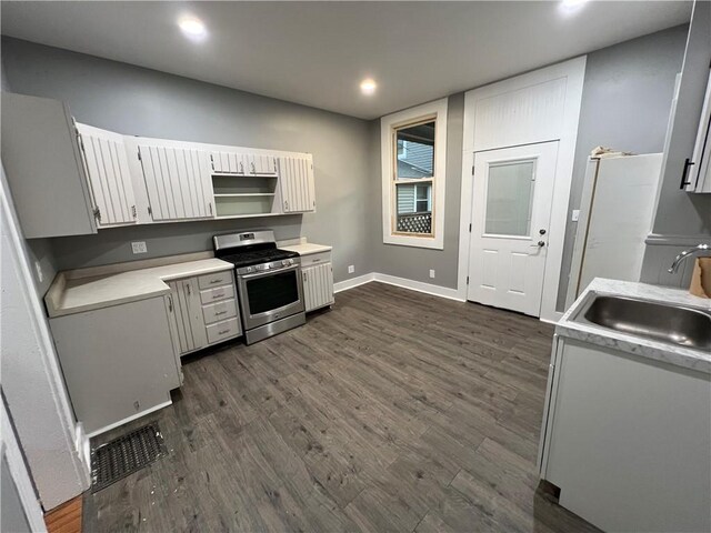 kitchen featuring sink, gas stove, dark wood-type flooring, and white cabinetry