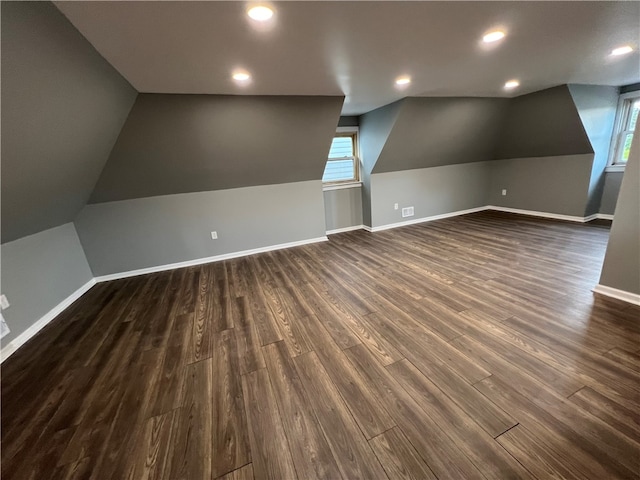 additional living space featuring plenty of natural light, vaulted ceiling, and dark hardwood / wood-style flooring